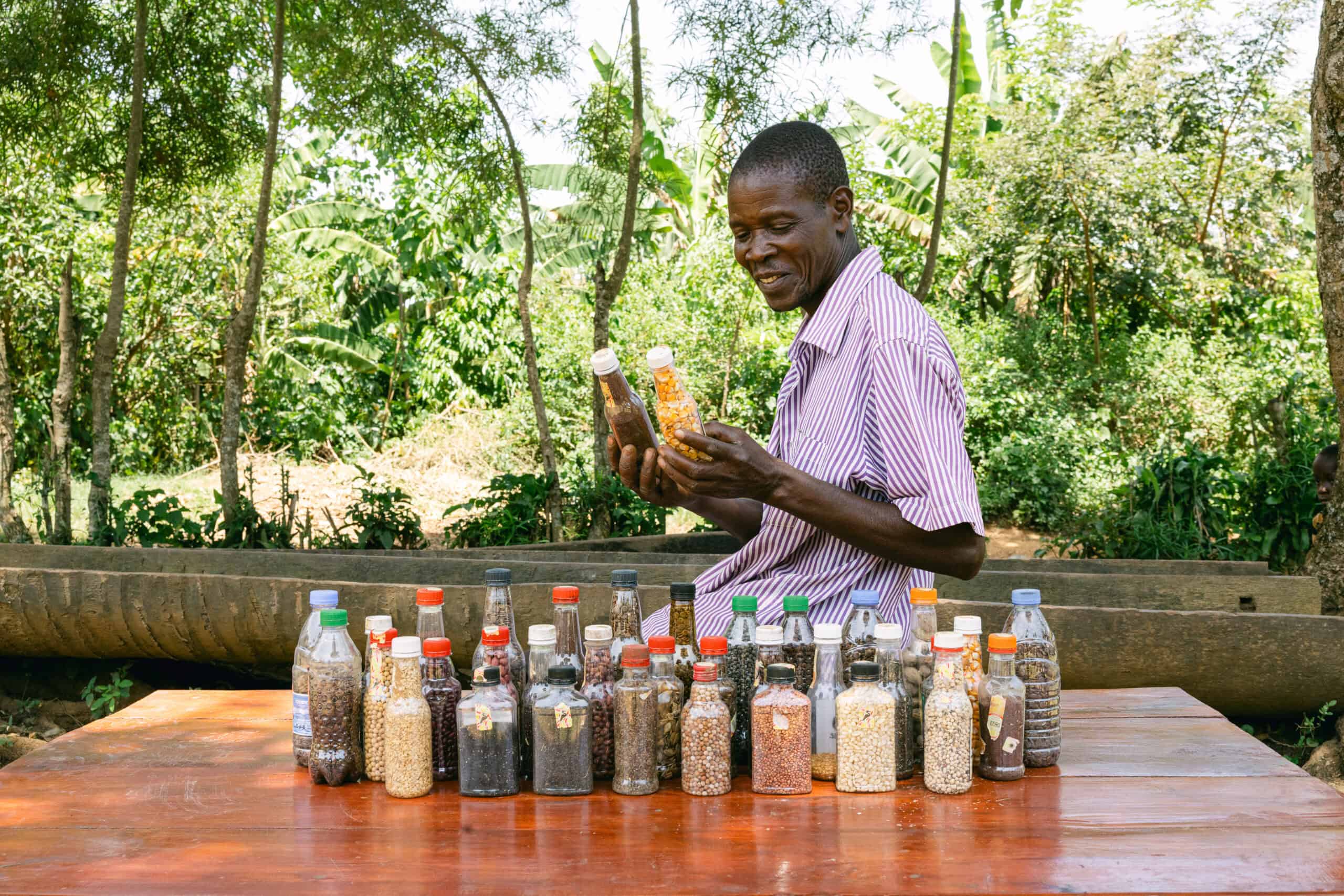 Farmer with seeds from Forest Garden in bottles for saving